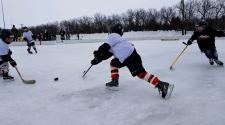 This image shows two players chasing the puck at youth pond hockey.