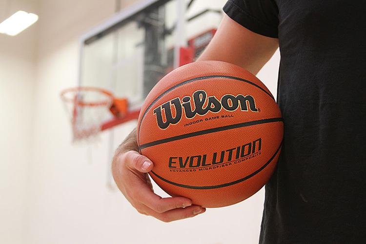 This image shows someone holding a basketball with the hoop in the background.