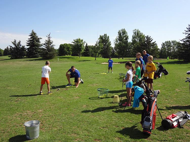 golfyouth2 This image shows the coach demonstrating while the group of kids watch during youth golf lessons.