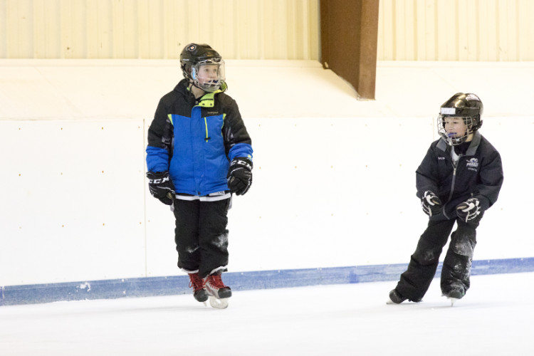 This image shows two boys skating at Open Hockey.