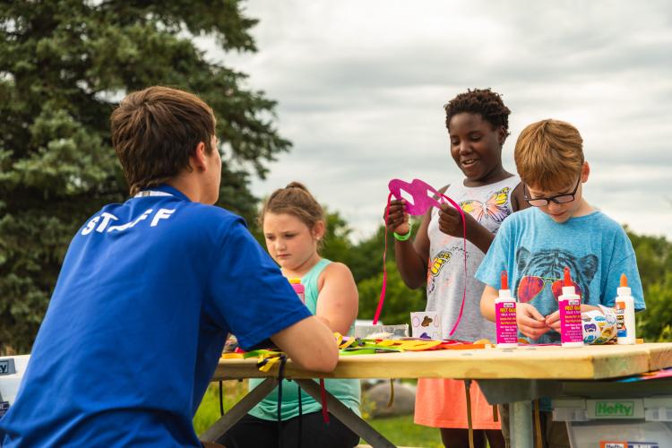 This image shows three kids working with an instructor at a craft table during Monstrous Imagination.
