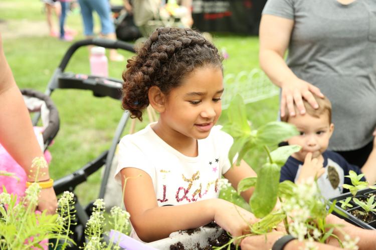 This image shows a girl picking a flower pot at a Hello Spring event.