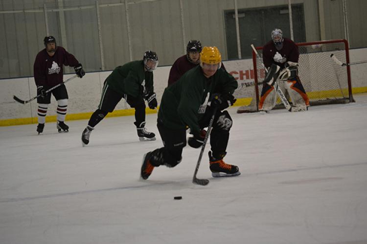 This image shows a player skating the puck up the ice at adult hockey.
