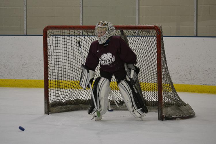 This image shows a goalie getting ready to make a save at youth hockey skills training.