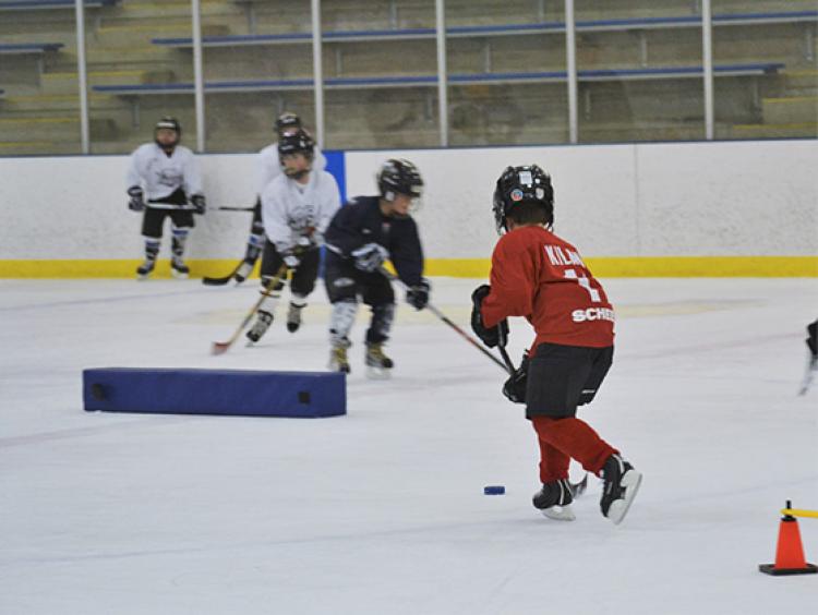 This image shows two kids doing a drill at youth hockey skills training.