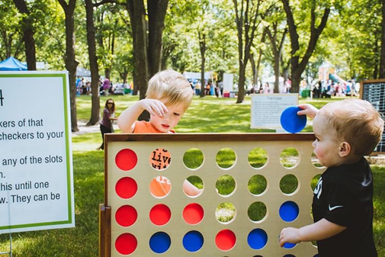 This image shows two boys playing giant, yard sized checkers at Midwest Kids Fest.