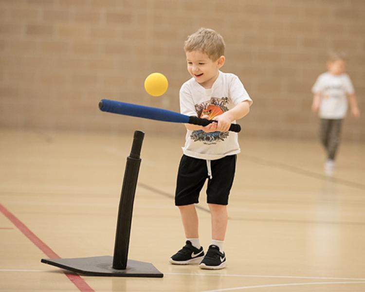 This image shows a boy hitting off the tee at the sports sampler.