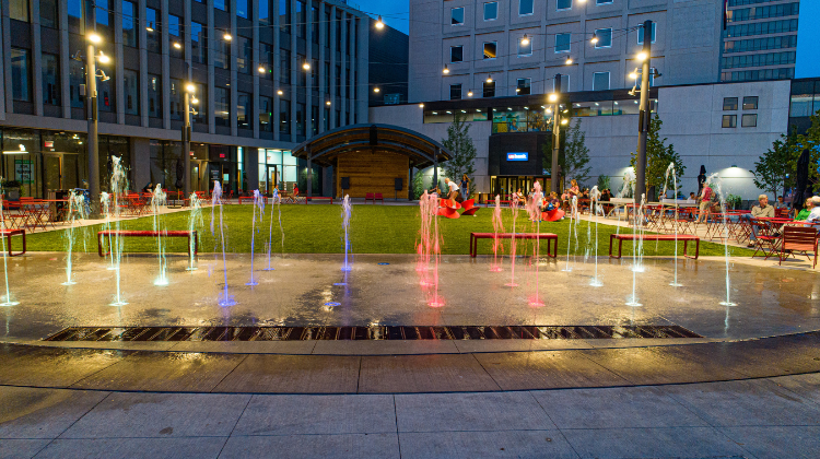 This image shows the Square Spouts at Broadway Square lit up during the night.
