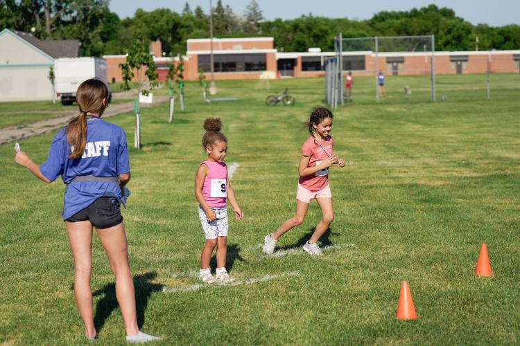 two kids at the starting line for race event in grass field for kids triathlon with Staff member calling go