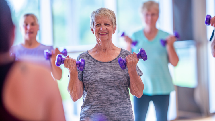 Senior woman lifting dumbbells in a group workout class.