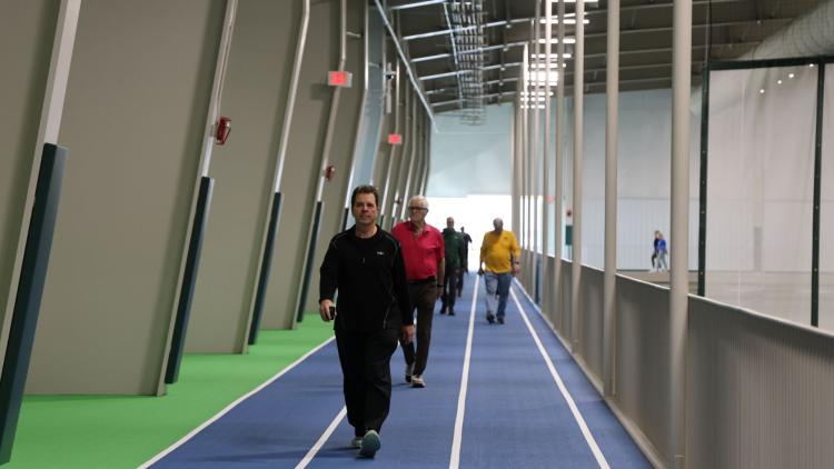 Several Adults walking on the indoor walking track at the Fargo Parks Sports Center.