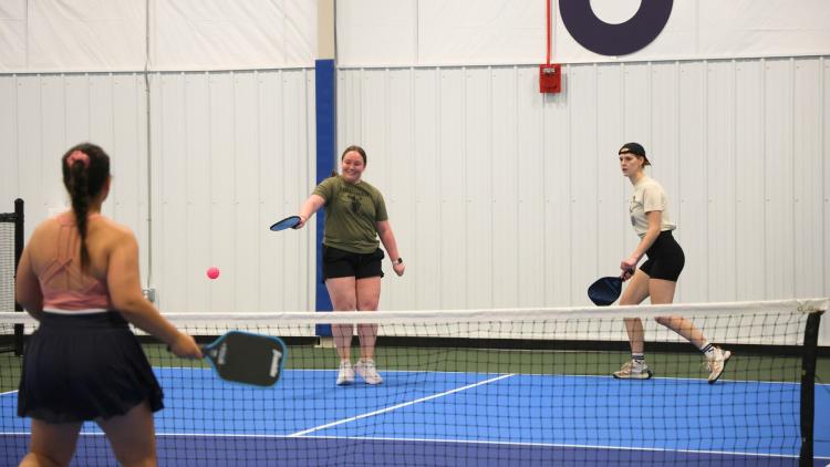 Three women playing pickleball on the Fargo Parks Sports Center pickleball courts