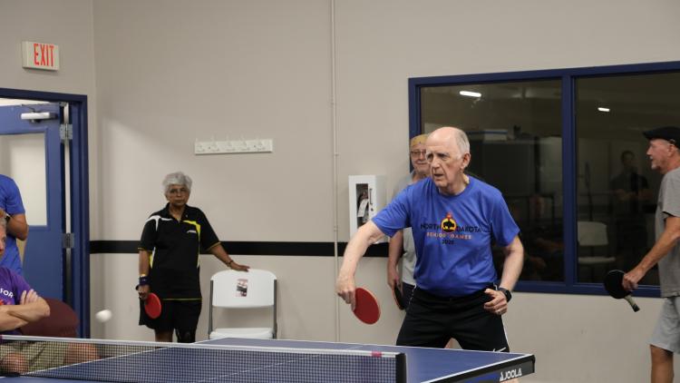 Senior athletes play table tennis indoors during the North Dakota Senior Games.