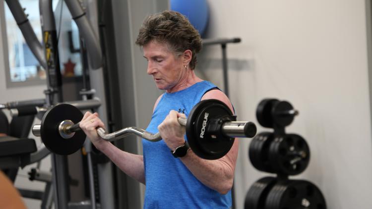 A woman lifts a barbell while strength training during the North Dakota Senior Games.
