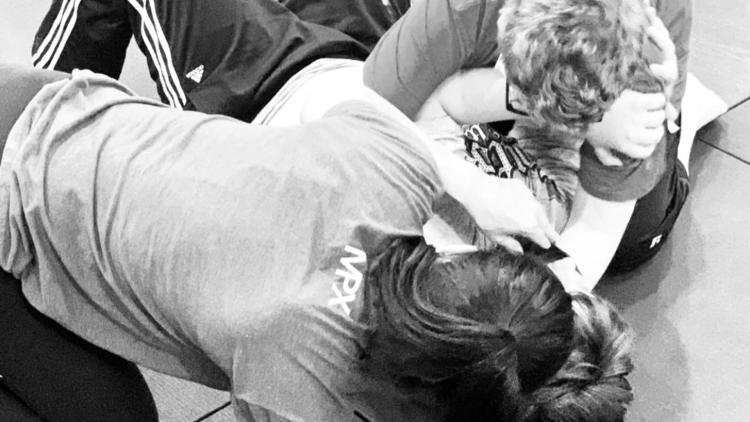 Participants practice hands-on self-defense techniques during a training session.