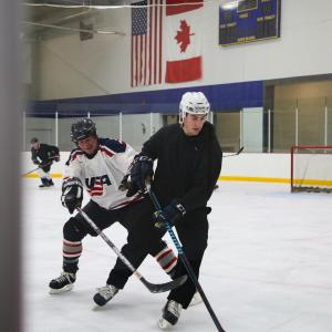This image shows men skating on the ice at Drop In Hockey.