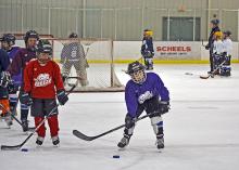 This image shows a group of players getting ready to start a drill at youth hockey skills training.