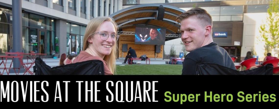 This image shows a graphic of "Movies at The Square Super Hero Series" on top of a photo of two people smiling at the camera as a movie plays on the Midco Mega Screen at Broadway Square.
