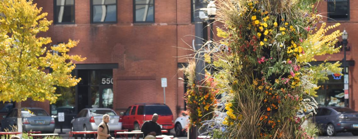 This image shows a fall floral installation on a light pole at broadway square