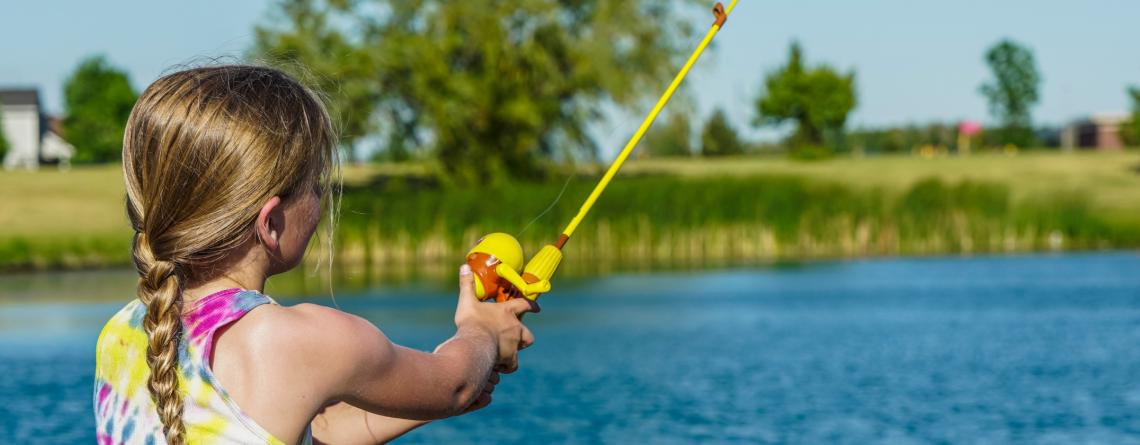 Young girl fishing at the pond. 
