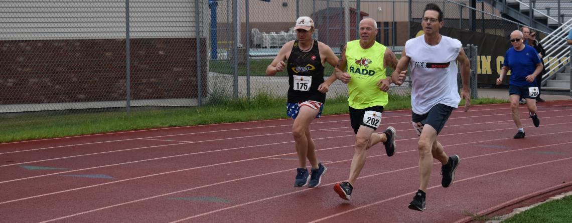 Photo of three senior athletes racing on a track. 