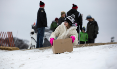 This image shows a child sledding in a cardboard box.