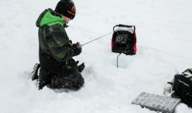 This image shows a picture of a child fishing at the Youth Ice Fishing Derby. 