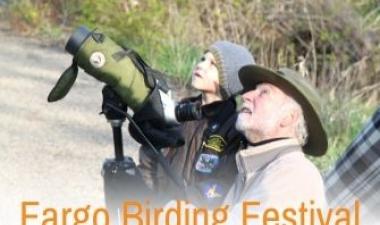 This image shows a young boy and a man looking up to the sky for birds during Fargo Birding Festival.