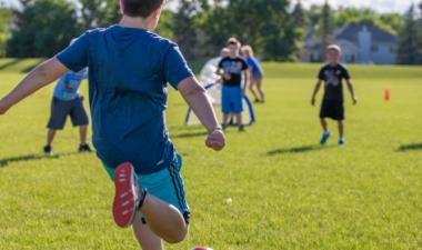 kid kicking soccer ball in park