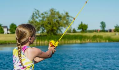 Young girl fishing at the pond. 