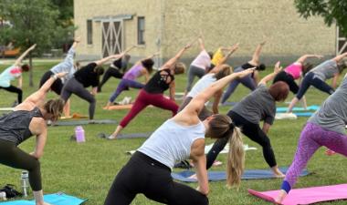 Large group of people doing outdoor yoga in a park