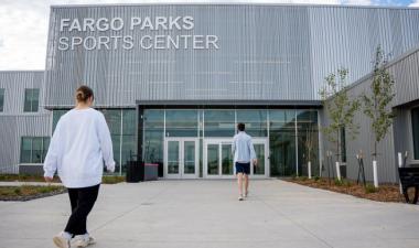 Two people walking into the main entrance of the Fargo Parks Sports Center