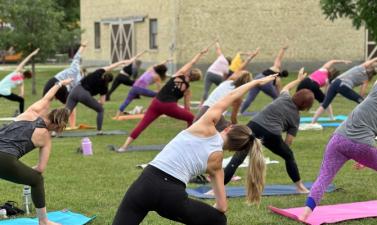Large group of people doing outdoor yoga in a park