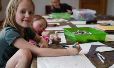 Children draw and create art together during a hands-on community education activity.