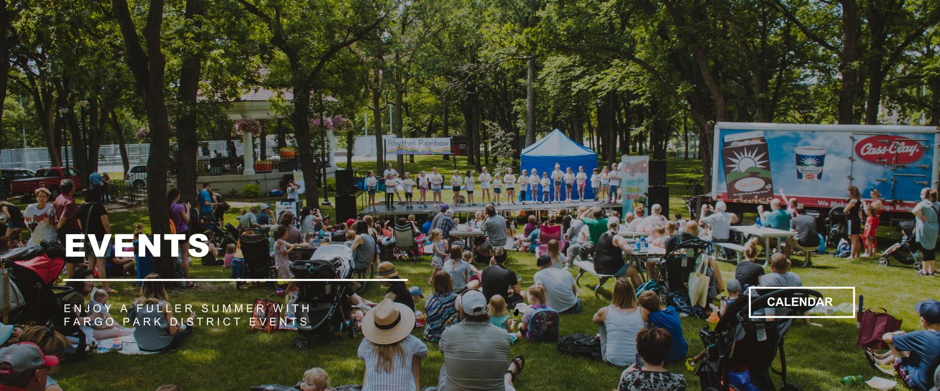 EVENTS - Enjoy a fuller summer with Fargo Park District Events - image of kids on a stage at Midwest Kid Fest in Island Park at a Penny & Pals show surrounded by hundreds of people sitting on the lawn listening