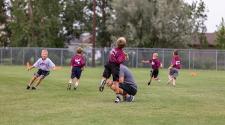This image shows a boy throwing the football to his teammates at the youth football program.