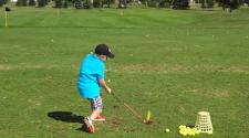 This image shows a young boy on the driving range during youth golf lessons.