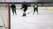 This image shows men skating on the ice at Drop In Hockey.