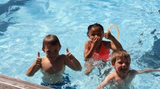 This image shows three kids swimming in a pool.