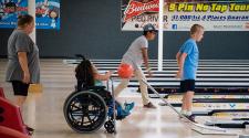 This image shows three kids bowling during the youth adaptive summer camp.
