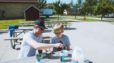 This image shows a boy and instructor making a craft during the youth adaptive summer camp.