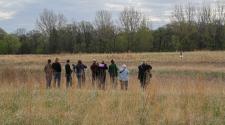 This image shows a group of people out in a field looking at flying birds during the birding program.