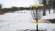 This image shows a disc golf basket during the winter.