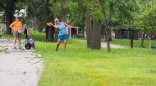 This image shows two females, one about to throw her frisbee at a disc golf tournament.