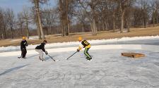 This image shows a player trying to score while another player tries defending at the Fargo Pond Hockey Classic.