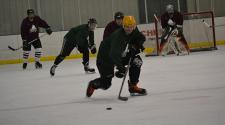 This image shows a player skating the puck up the ice at adult hockey.