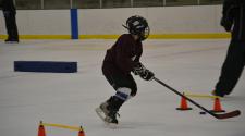 This image shows a boy doing a cone drill at youth hockey skills training.