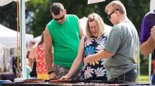 This image shows three people checking out the items at one of the vendor booths at Island Park Show.