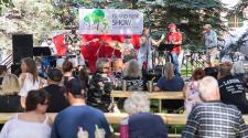 This image shows the band playing music in front of a crowd at Island Park Show.