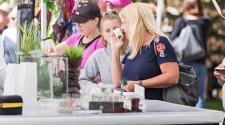 This image shows two people smelling items at a vendor booth at Island Park Show.